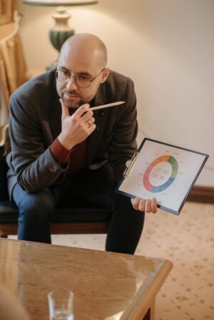 pensive man sitting on chair holding a clipboard and pen