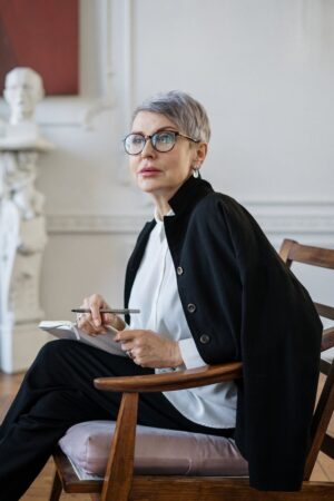 woman in black blazer sitting on brown wooden chair